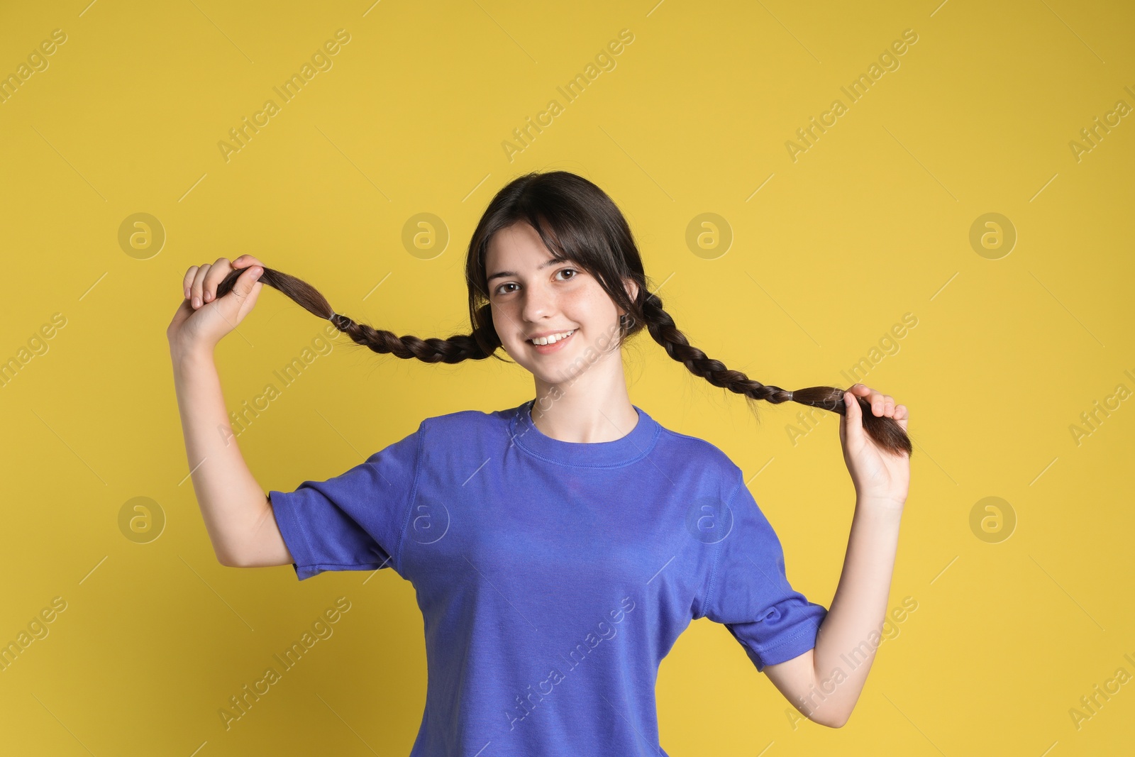 Photo of Portrait of smiling teenage girl on yellow background