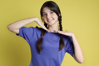 Portrait of smiling teenage girl on yellow background