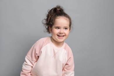 Photo of Adorable child. Portrait of happy girl on grey background. Space for text