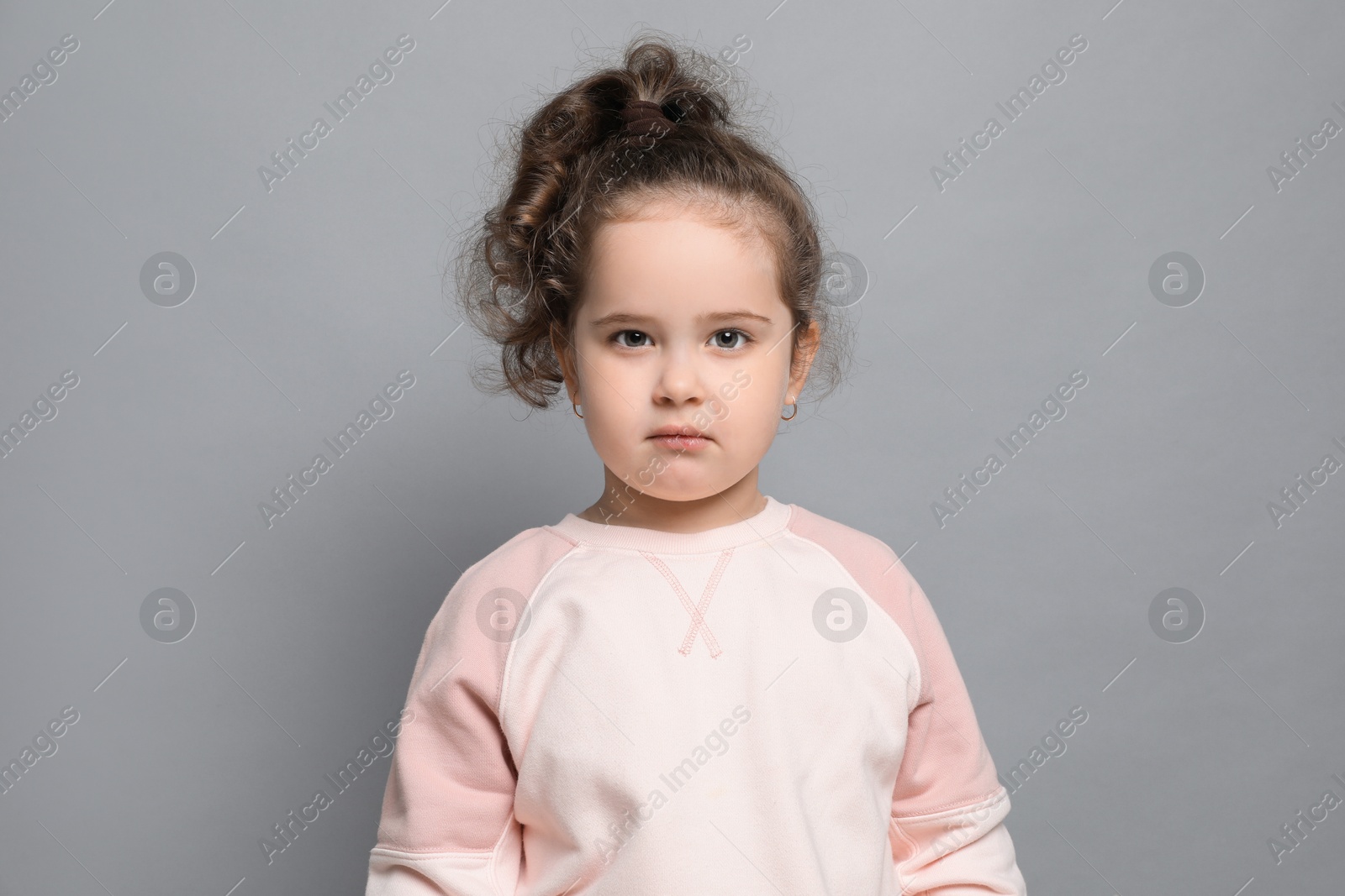 Photo of Adorable child. Portrait of cute girl on grey background