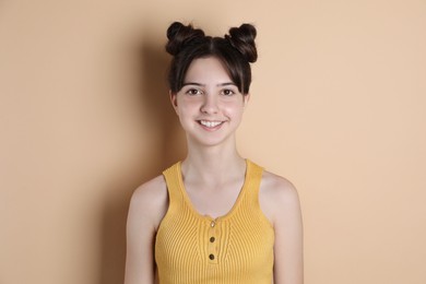 Portrait of smiling teenage girl on beige background