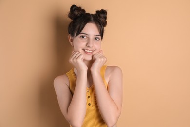 Portrait of smiling teenage girl on beige background