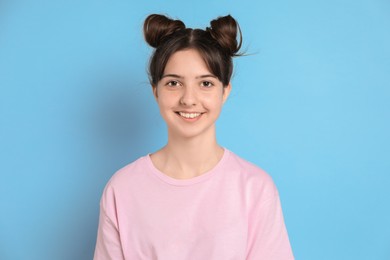 Portrait of smiling teenage girl on light blue background