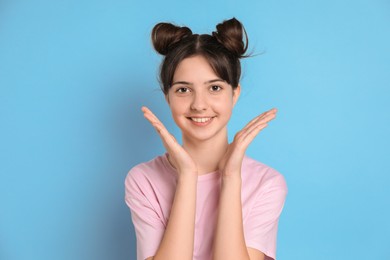 Portrait of smiling teenage girl on light blue background