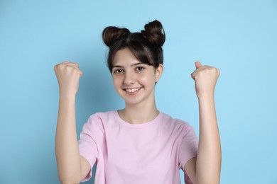 Portrait of smiling teenage girl on light blue background