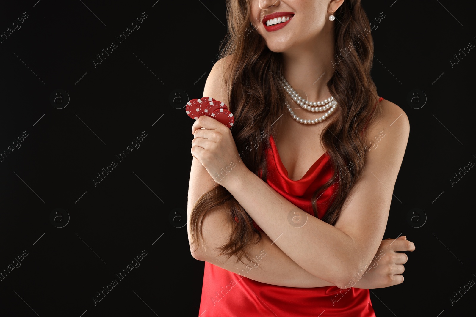 Photo of Smiling woman with poker chips on black background, closeup. Space for text