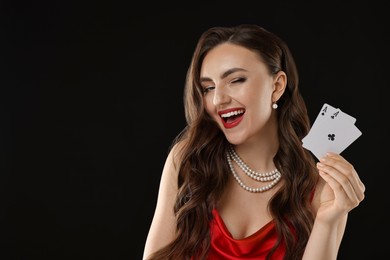 Photo of Poker game. Happy woman with playing cards on black background. Space for text