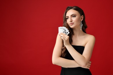 Photo of Poker game. Charming woman with playing cards on red background. Space for text