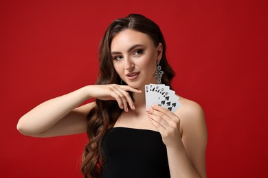 Photo of Poker game. Charming woman pointing at playing cards on red background