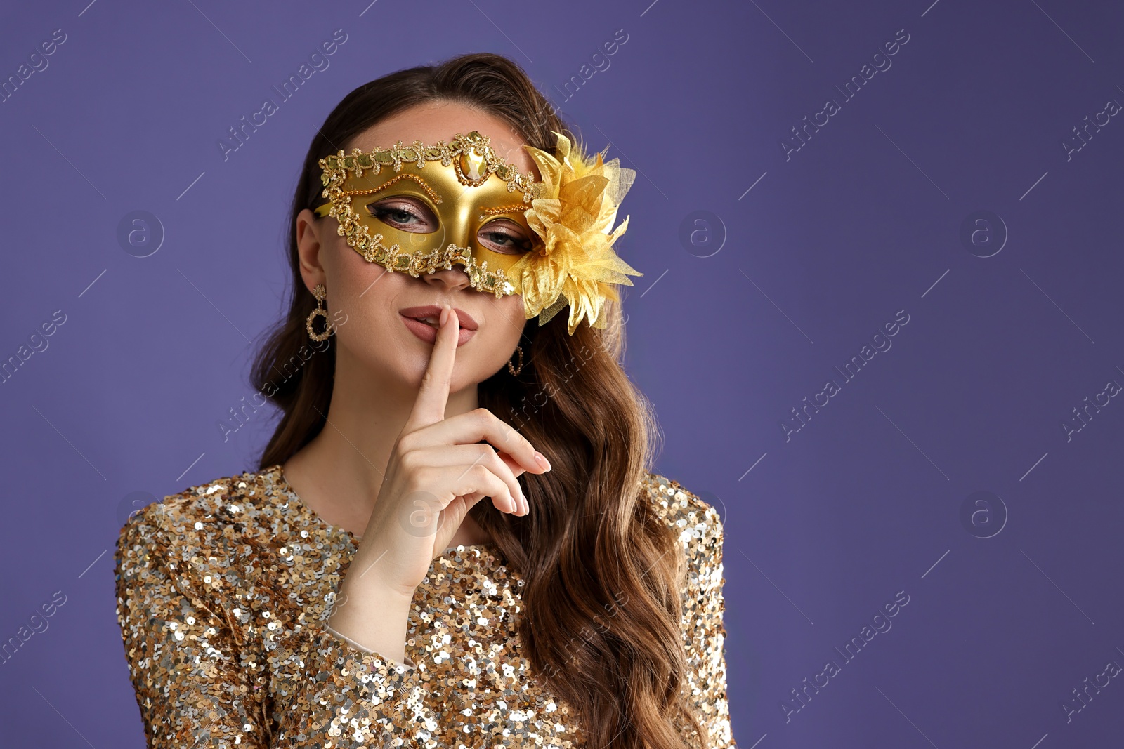 Photo of Beautiful woman with carnival mask showing hush gesture on purple background. Space for text