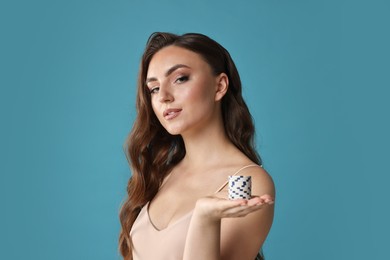 Charming woman with poker chips on light blue background