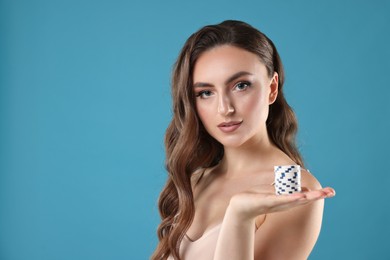 Photo of Charming woman with poker chips on light blue background. Space for text