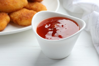 Photo of Spicy chili sauce in bowl on white wooden table, closeup