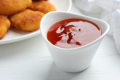 Photo of Spicy chili sauce in bowl on white wooden table, closeup