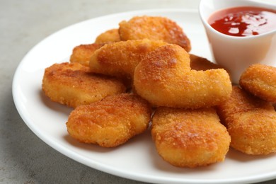 Photo of Tasty chicken nuggets with chili sauce on grey table, closeup