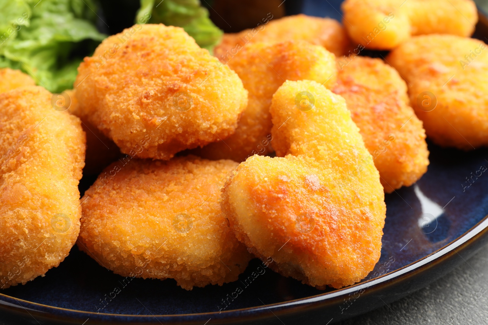 Photo of Tasty chicken nuggets on grey table, closeup