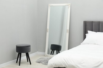 Photo of Large mirror near grey wall in bedroom. Interior design