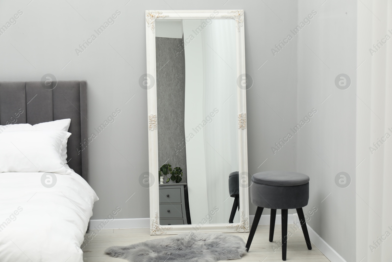 Photo of Large mirror near grey wall in bedroom. Interior design