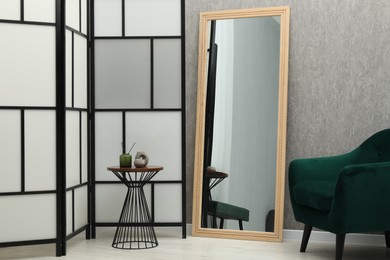 Photo of Large mirror near grey wall in room. Interior design