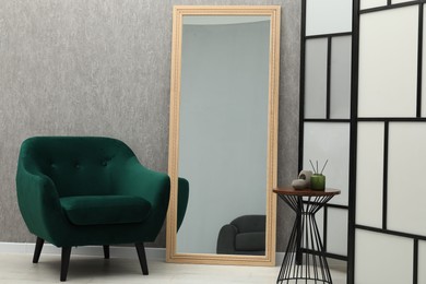 Photo of Large mirror near grey wall in room. Interior design