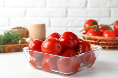 Photo of Tasty pickled tomatoes in bowl on white table