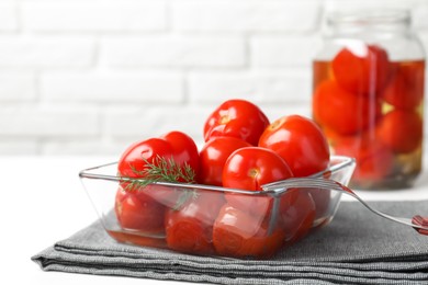 Tasty pickled tomatoes, dill and fork on white table