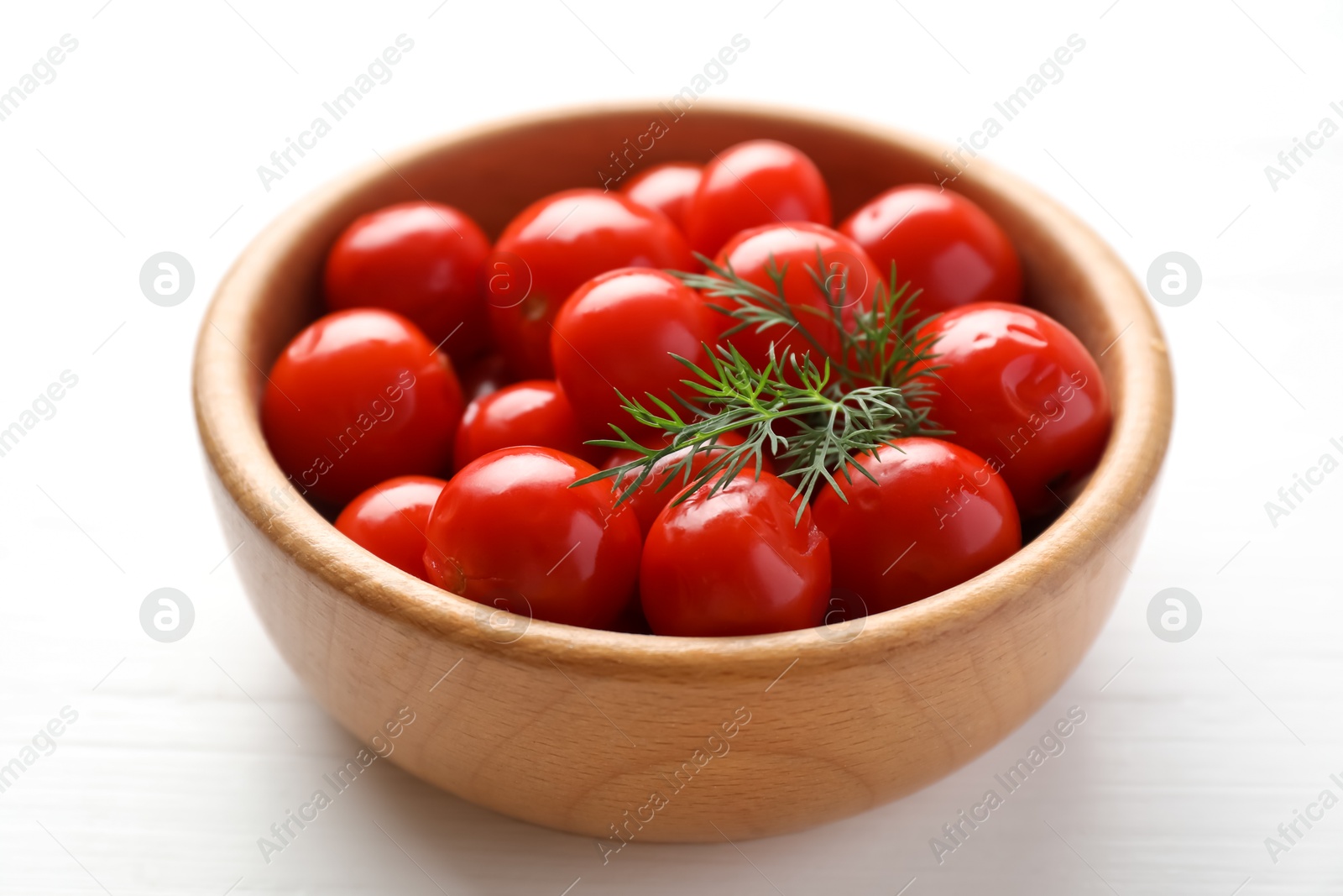 Photo of Tasty pickled tomatoes and dill in bowl on white wooden table, closeup