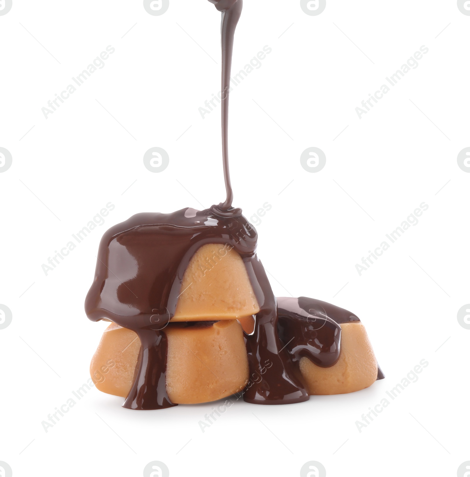 Photo of Pouring delicious melted chocolate onto caramel candies isolated on white