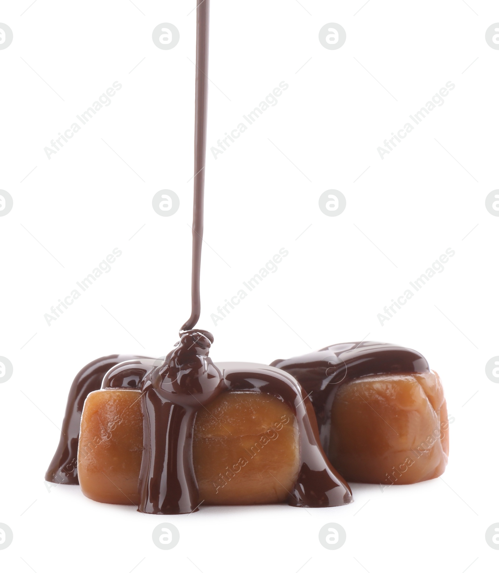 Photo of Pouring delicious melted chocolate onto caramel candies isolated on white