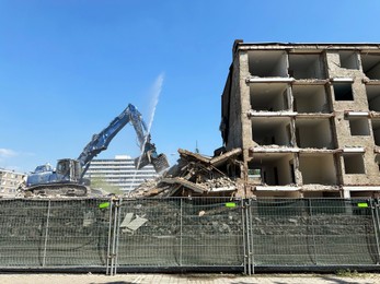 Demolition of building with excavator under blue sky