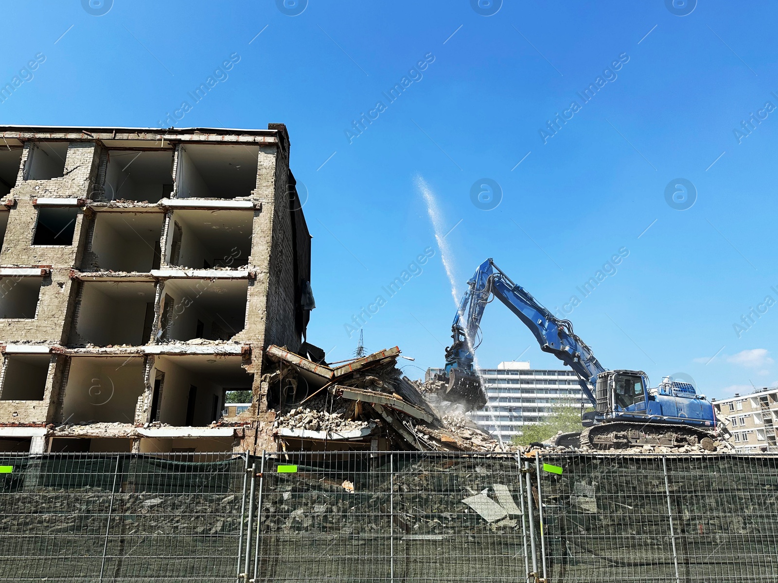 Photo of Demolition of building with excavator under blue sky