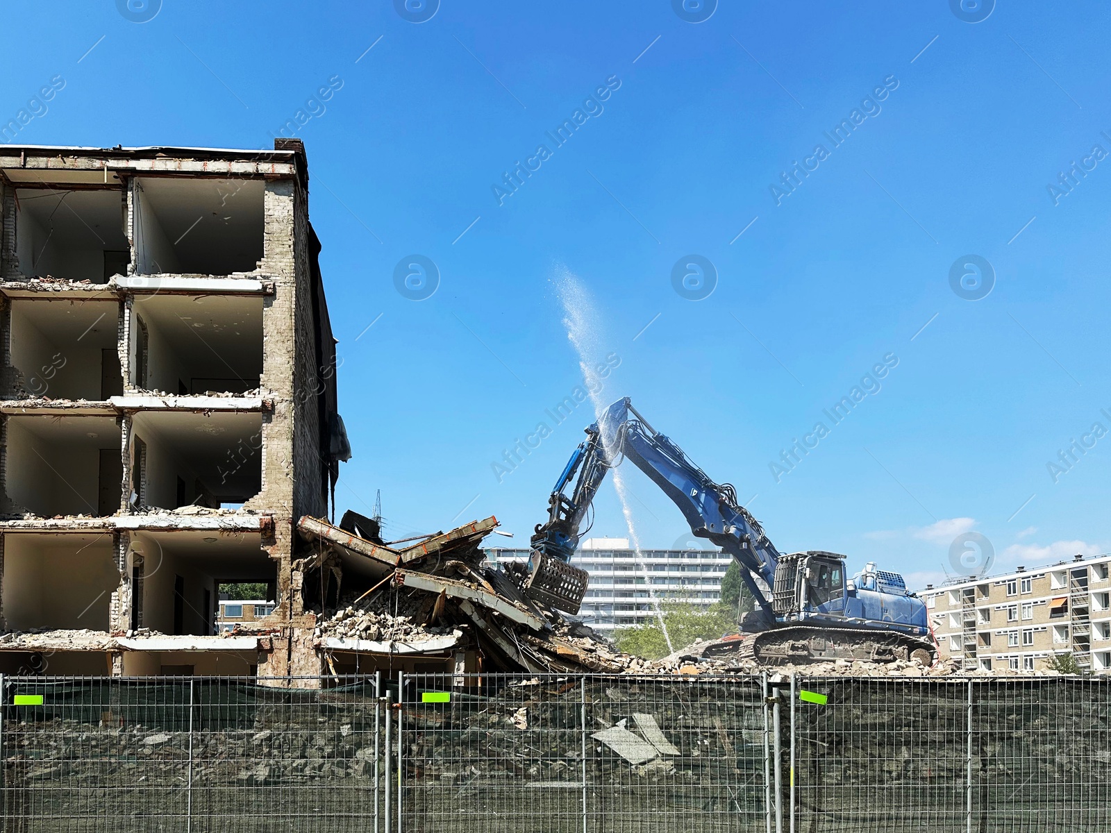 Photo of Demolition of building with excavator under blue sky