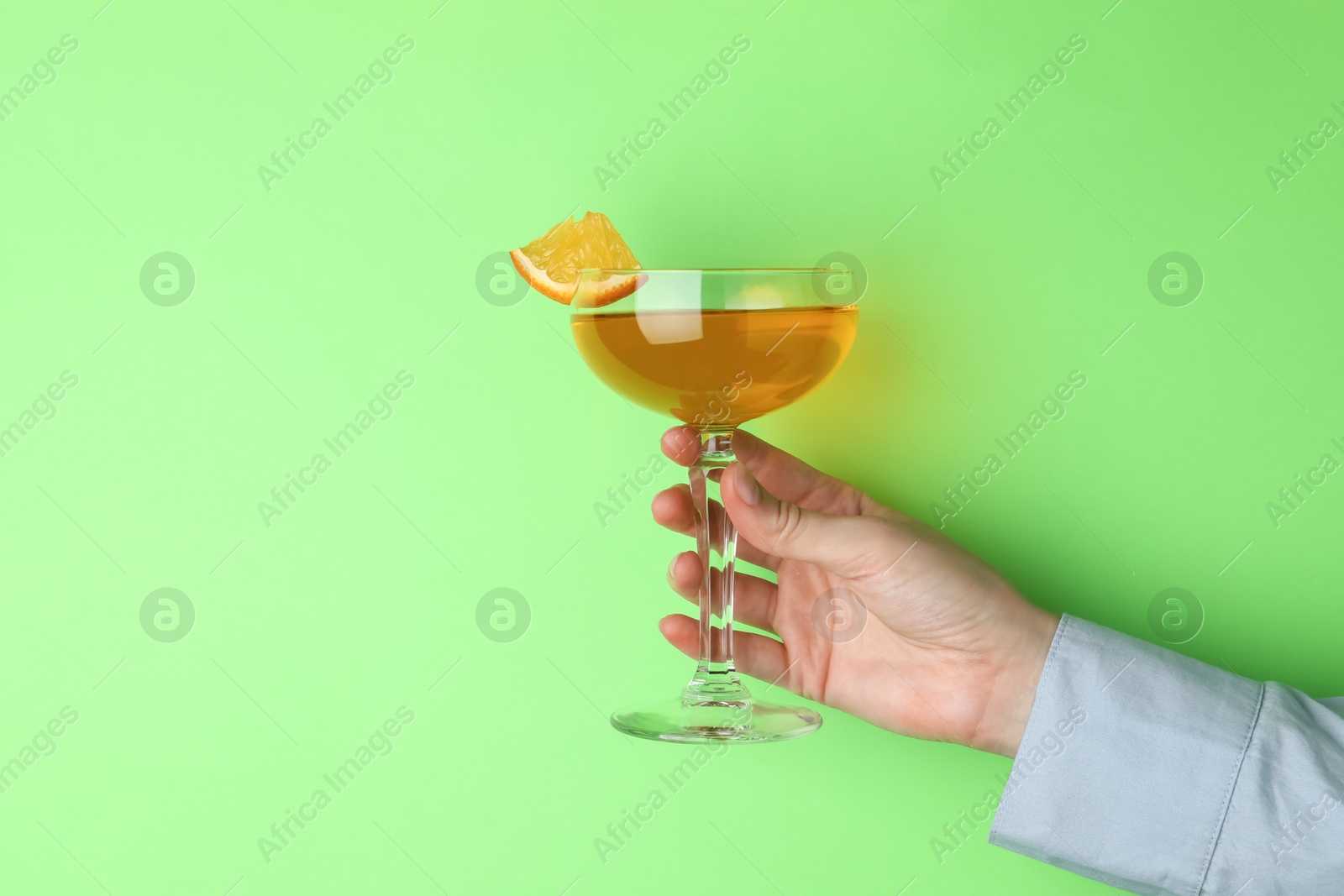 Photo of Woman with glass of refreshing cocktail on green background, closeup