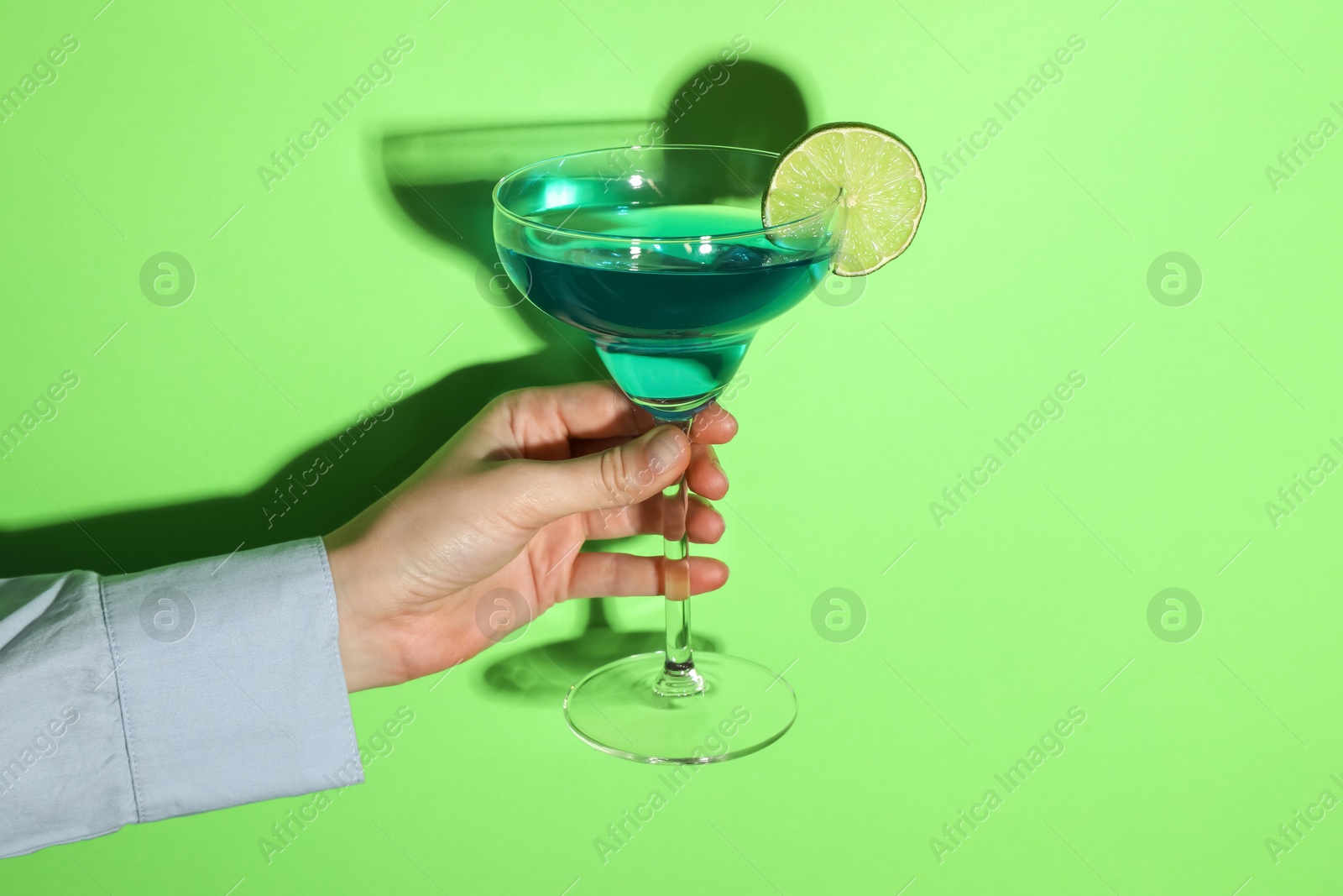 Photo of Woman with glass of refreshing cocktail on green background, closeup