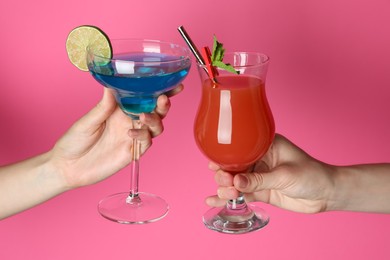 Photo of Friends with glasses of refreshing cocktails on pink background, closeup