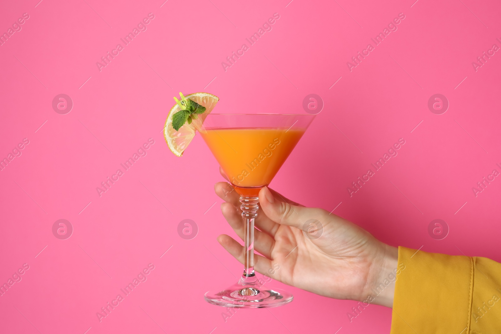 Photo of Woman with glass of refreshing cocktail on pink background, closeup