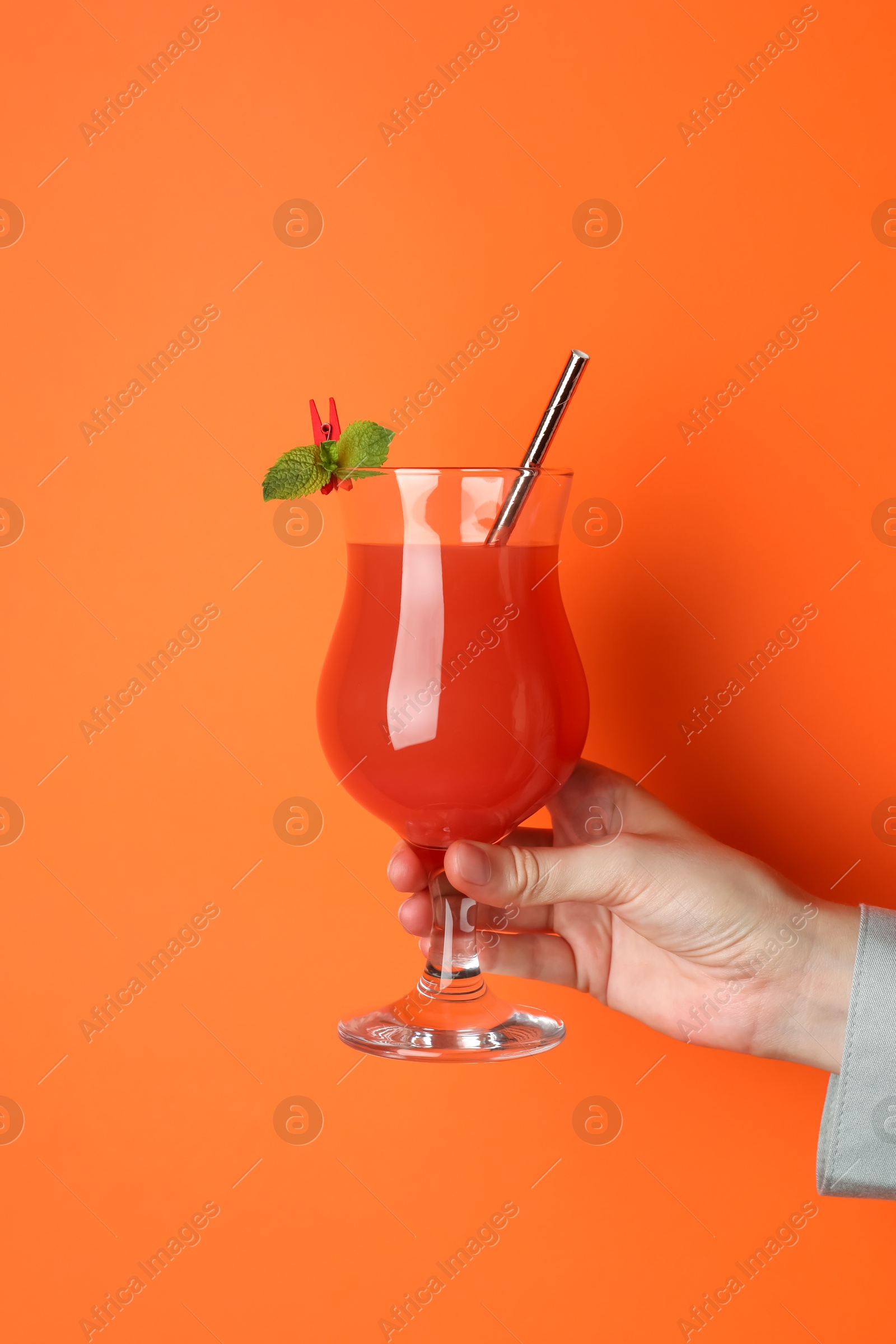 Photo of Woman with glass of refreshing cocktail on orange background, closeup