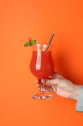 Photo of Woman with glass of refreshing cocktail on orange background, closeup