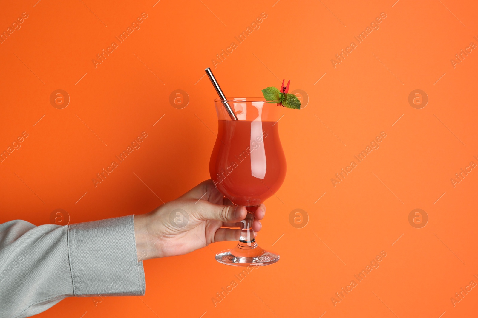 Photo of Woman with glass of refreshing cocktail on orange background, closeup