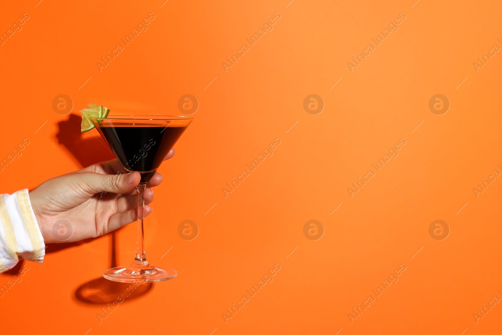 Photo of Woman with glass of refreshing cocktail on orange background, closeup. Space for text