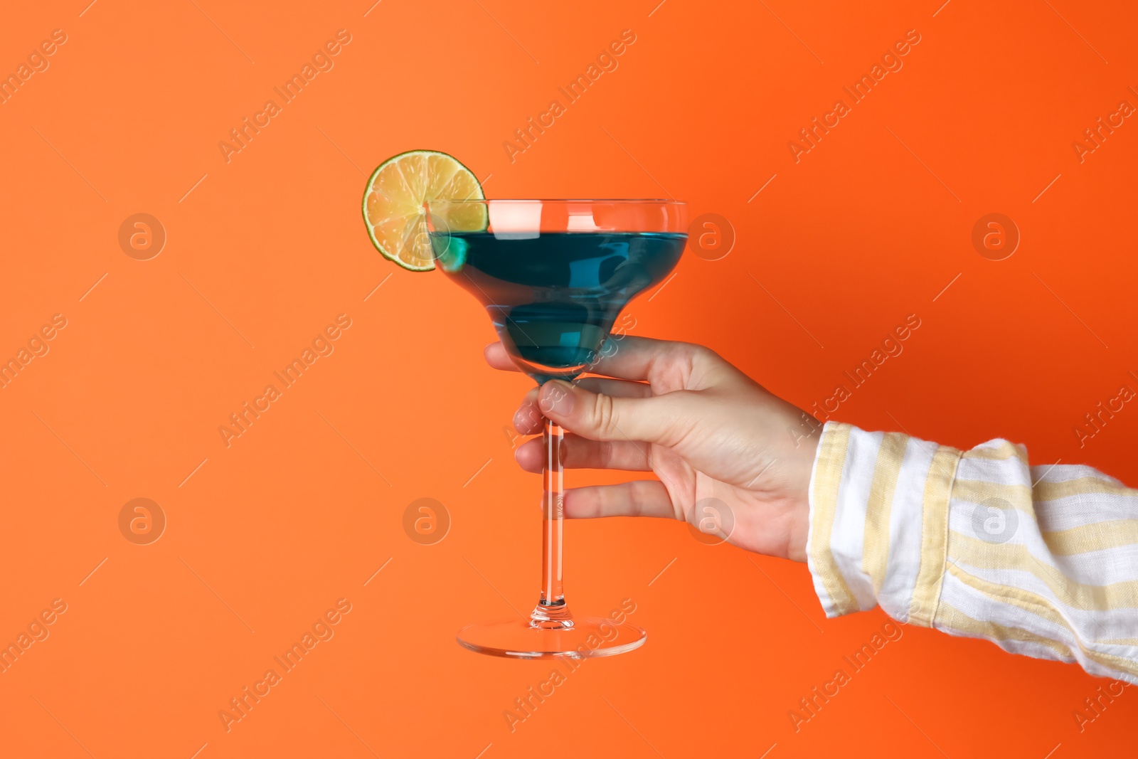 Photo of Woman with glass of refreshing cocktail on orange background, closeup