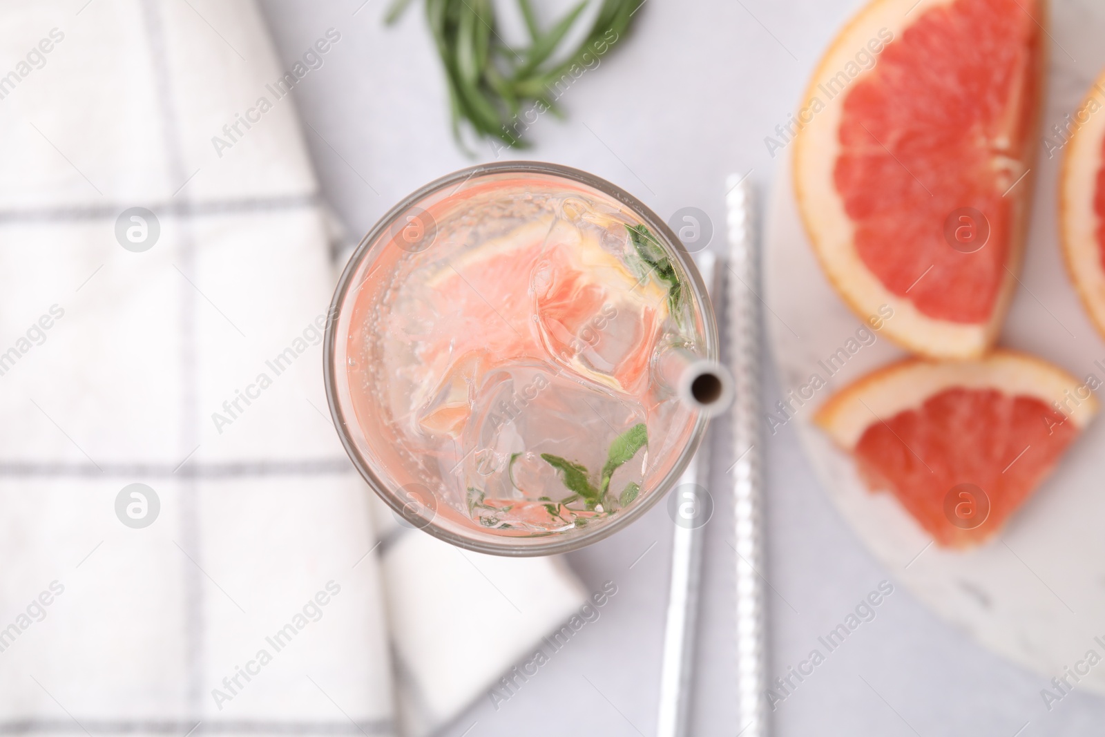 Photo of Refreshing water with grapefruit and rosemary in glass on light table, flat lay