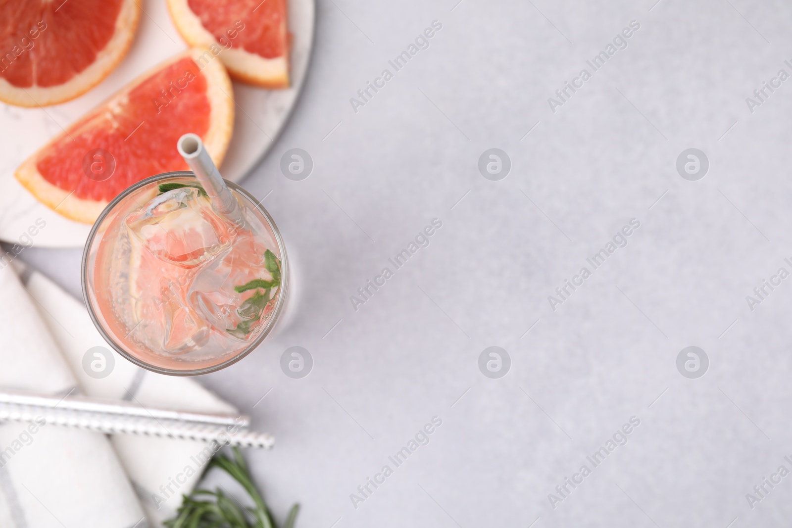 Photo of Refreshing water with grapefruit and rosemary in glass on light table, flat lay. Space for text