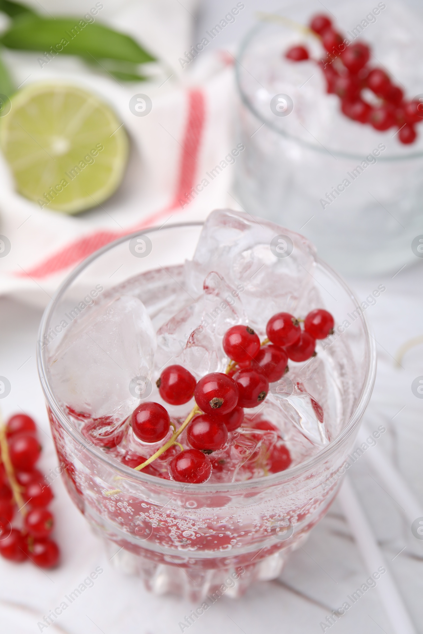 Photo of Refreshing water with red currants in glass on light table, closeup