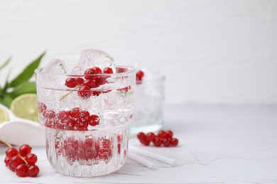 Photo of Refreshing water with red currants in glass on light table, space for text