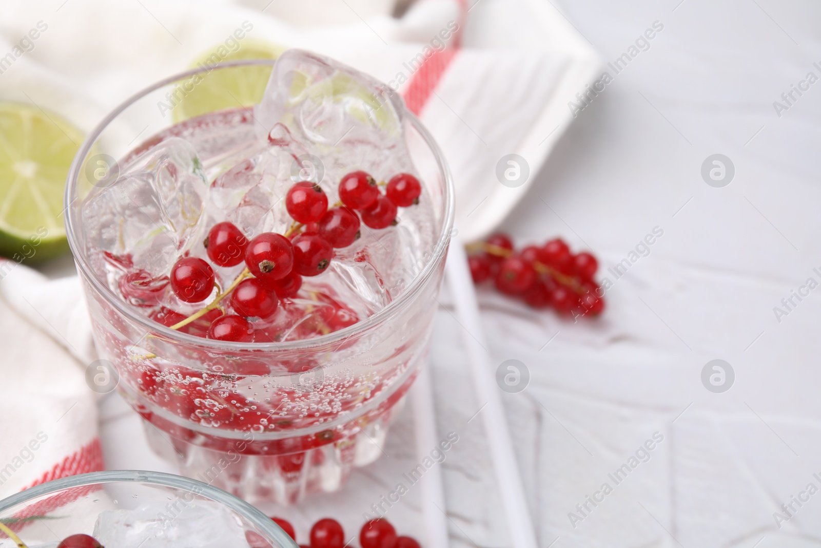 Photo of Refreshing water with red currants in glass on light table, closeup. Space for text