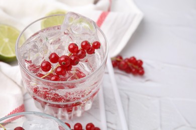 Photo of Refreshing water with red currants in glass on light table, closeup. Space for text