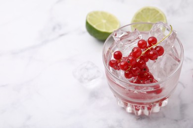 Photo of Refreshing water with red currants in glass on white marble table, closeup. Space for text