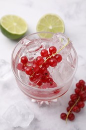 Photo of Refreshing water with red currants in glass on white marble table, closeup