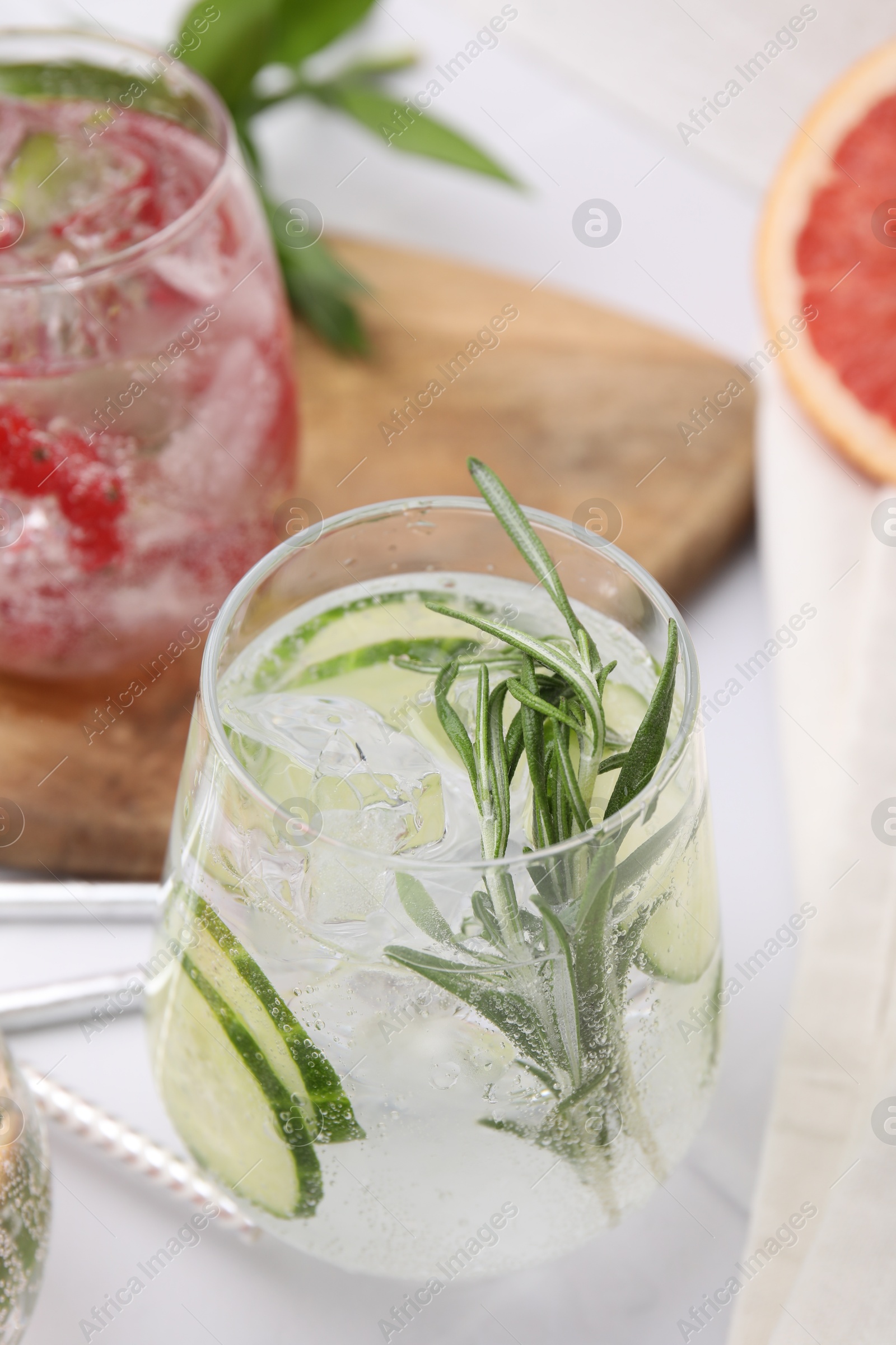 Photo of Different refreshing drinks in glasses on white tiled table, closeup